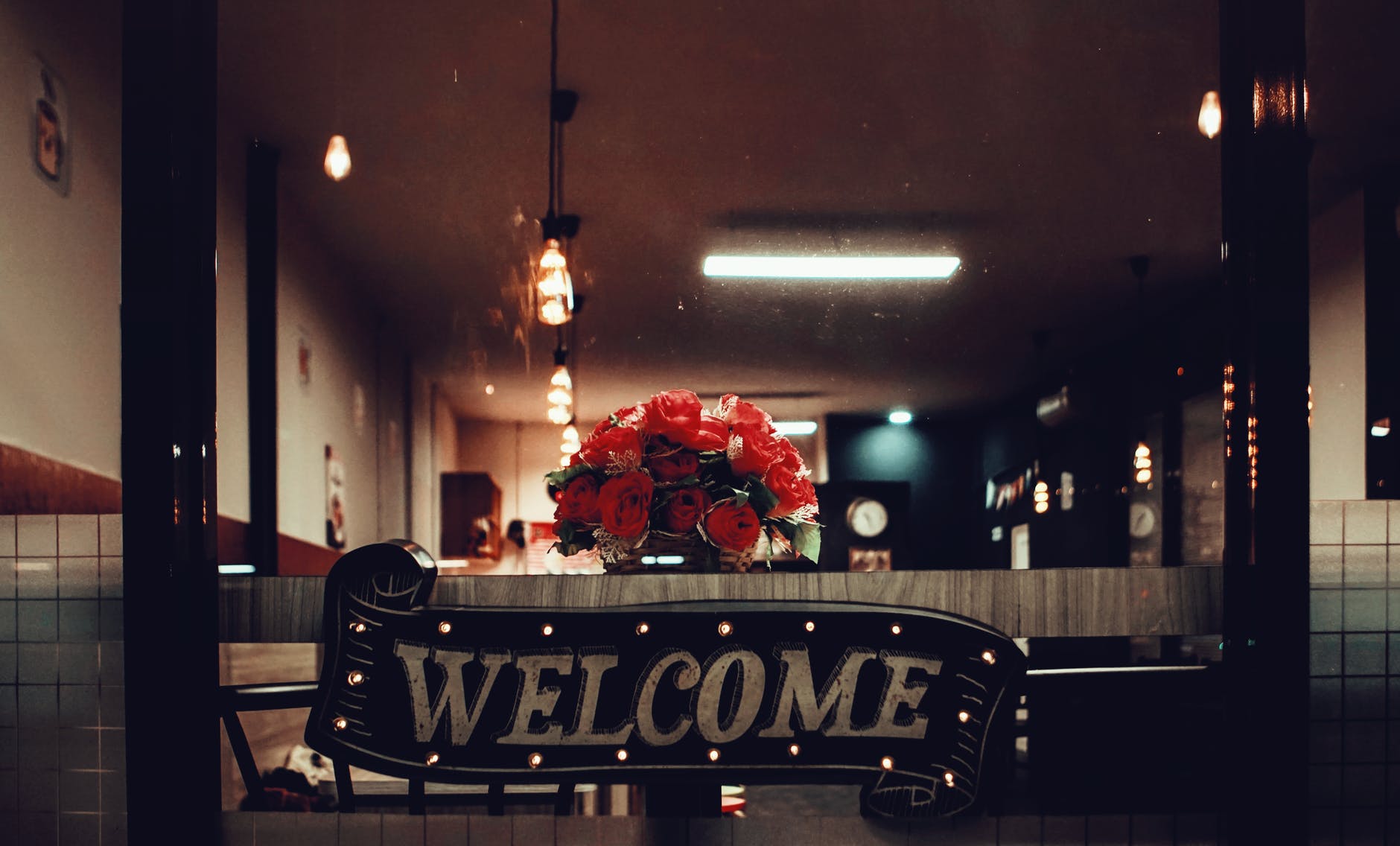 black welcome signage under pendant lamp photography