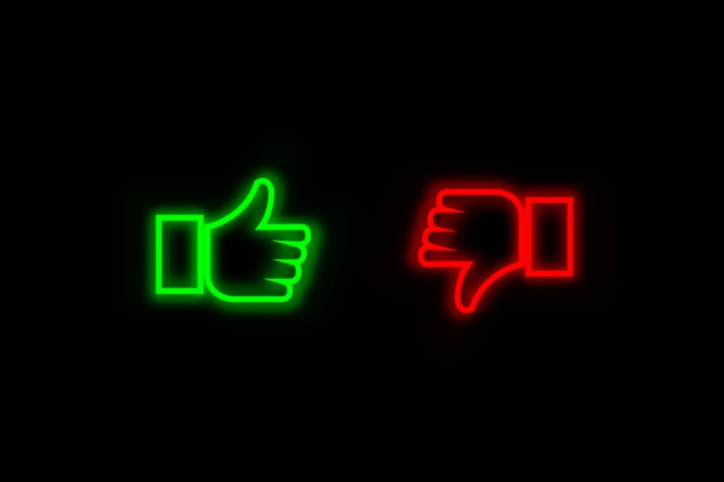 a black background with neon drawings of a thumbs-up in green and a thumbs-down in red